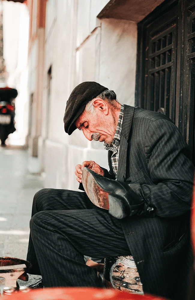 Hombre anciano con un zapato en las manos ejerciendo su oficio
